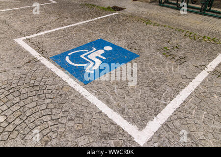 Zugänglich Parkplatz für Menschen mit Behinderung reserviert. Blaues Quadrat mit einer Person in einem Rollstuhl auf einem Kopfsteinpflaster gemalt Stockfoto