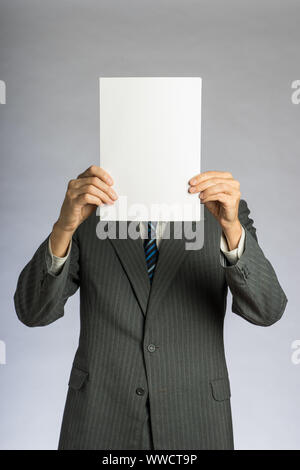 Geschäftsmann Holding ein Weißbuch vor den Kopf. Leeres Blatt und Mann in Anzug. Stockfoto