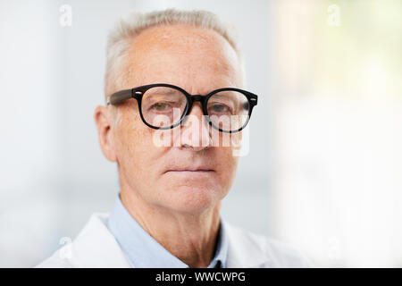 Kopf und Schultern Portrait von weißen Haaren leitender Arzt Brille und Kamera beim Posieren in Büro, Kopie Raum Stockfoto