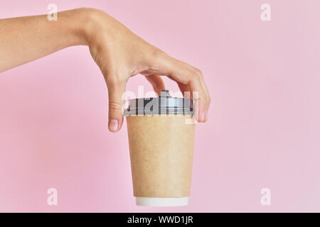 Mockup der weiblichen Hand Kaffee Pappbecher auf einem rosa Hintergrund. Stockfoto