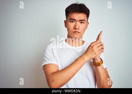 Jungen asiatischen Chinesischer Mann tragende t-shirt stehend über isoliert weißer Hintergrund Holding symbolische Waffe mit Geste, spielend töten Schießen weapo Stockfoto