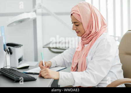 Porträt der jungen des Nahen Ostens Frau mit Kopftuch arbeiten als Krankenschwester in der Medizinischen Klinik und Patienten Form am Schreibtisch, kopieren Raum Stockfoto