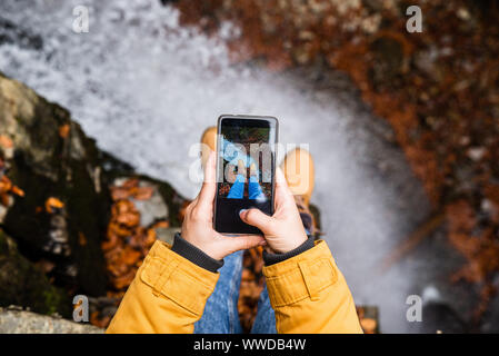 Die Frau am Telefon Ihrer Beine mit Wasserfall im Hintergrund Stockfoto