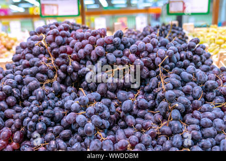 Großer Berg des schwarzen Trauben, Zähler Vitrine im Supermarkt, umweltfreundlich und nützliches Produkt im Store. Stockfoto