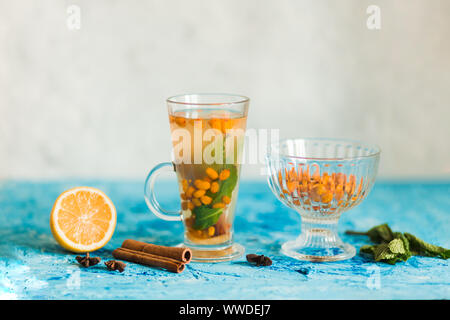 Leckere Sanddorn Tee mit Zimt, Zitrone und Limette, Minze auf dem blauen Tisch in der Küche, zu kopieren. Die richtige Ernährung, leckeres Essen Stockfoto