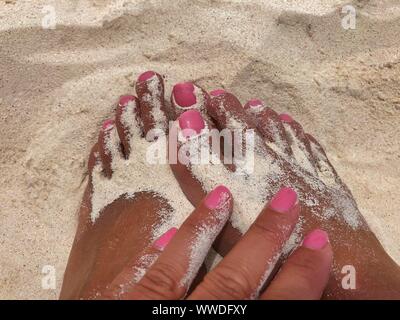 Eine Frau Hand berühren die Füße im Sand, Tulum, Yucatan, Mexiko Stockfoto