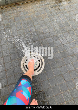 Woman's Bein über einen Springbrunnen in der Straße, Litauen Stockfoto