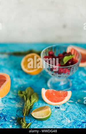 Nahaufnahme der Hälfte rote reife Grapefruit auf blauem Hintergrund mit Minze und Obst Stockfoto