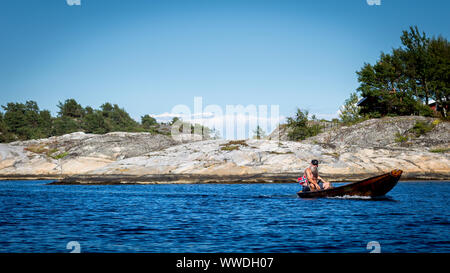 Man Segeln eine hölzerne Beiboot außerhalb Korset bei Skatoy in Norwegen, mit 5 PS Außenbordmotor ausgestattet. Das Design ist typisch für kleine norwegische Boote aus Holz. Stockfoto