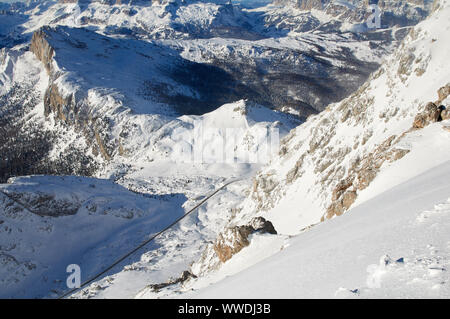 Panoramablick vom Berg Lagazuoi auf der Straße zum Valparola Pass zwischen den verschneiten Bergen, mit einem einzigen Bus auf der Passstraße. Stockfoto