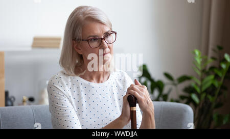 Reife Frau mit Holz- Zuckerrohr umgekippt, Überlegungen über die künftigen Stockfoto