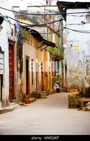 Stone Town, Tansania - Januar 10, 2016: ein Mann sitzt an der Tür seines Geschäftes mit Geschenken für Touristen in Stone Town, Sansibar. Tansania Stockfoto