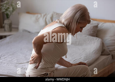 Verärgert reife Frau leiden unter Rückenschmerzen, reibt steifen Muskeln Stockfoto
