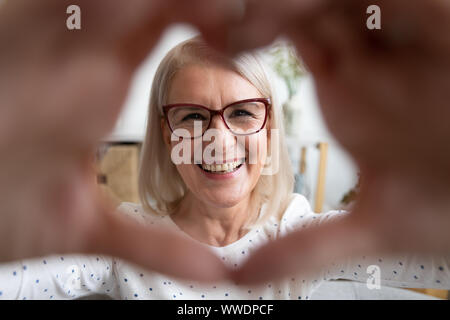 Porträt Lächeln reife Frau durch die Herzförmigen Hände Stockfoto