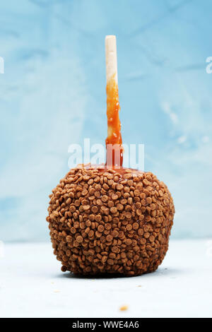 Leckere Karamell Apfel mit Holz Stick mit Samen, vor blauem Hintergrund fotografiert eingerichtet Stockfoto