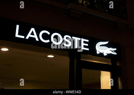 Lugano, Tessin, Schweiz - 17 August 2019: Blick auf das beleuchtete Lacoste Marke Logo vor dem Store in Lugano hängen. Lacoste ist eine Fren Stockfoto