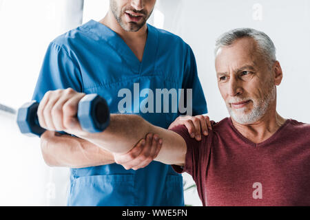 Der Arzt in der Nähe von reifen Mann mit hantel 7/8 Stockfoto