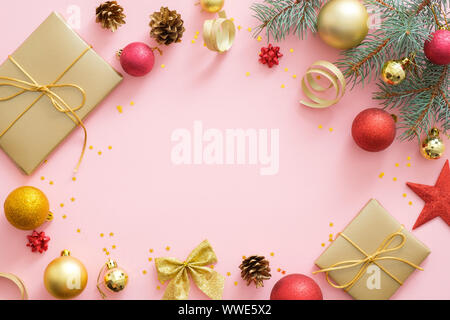 Flatlay Weihnachtsferien Zusammensetzung auf Pastell rosa Hintergrund mit kopieren. Ansicht von oben Xmas Tree Tannenzweigen, roten und goldenen Kugeln, Geschenkbox, Pon Stockfoto