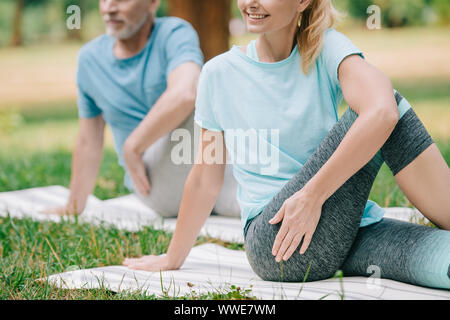 Teilweise mit Blick auf die reifen Mann und Frau praktizieren von Yoga auf Rasen im Park Stockfoto