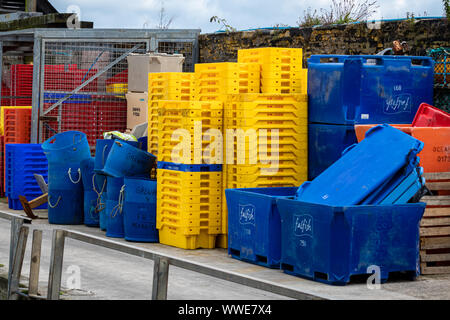 Kran und gestapelten Fisch Aufbewahrungsboxen in Gelb, Blau und Orange auf der Hafenmauer in Mevagissey Cornwall GROSSBRITANNIEN Stockfoto