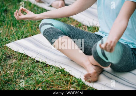 7/8-Ansicht von Frau und Mann Meditation in Lotus Posen auf Yoga Matten Stockfoto