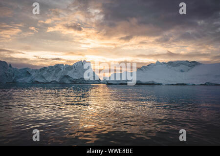 Arktische Natur Landschaft mit Eisbergen in Grönland Eisfjord mit 24.00 Uhr Sonne Sonnenuntergang Sonnenaufgang am Horizont. Am frühen Morgen Sommer alpenglow während Stockfoto