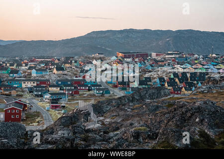 Luftaufnahme der arktischen Stadt Ilulissat, Grönland bei Sonnenaufgang Sonnenuntergang mit Nebel. Bunte Häuser im Zentrum der Stadt mit Eisbergen in der Stockfoto