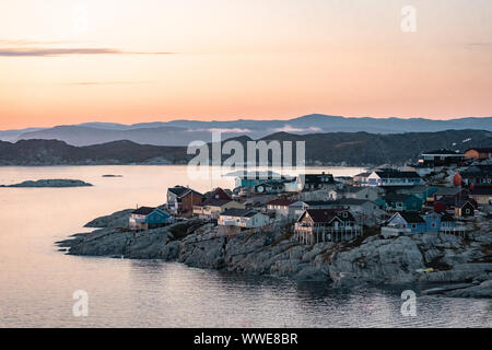 Luftaufnahme der arktischen Stadt Ilulissat, Grönland bei Sonnenaufgang Sonnenuntergang mit Nebel. Bunte Häuser im Zentrum der Stadt mit Eisbergen in der Stockfoto