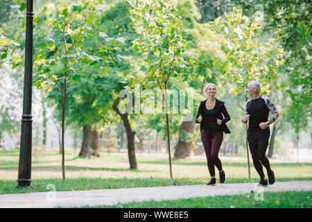 Sportliche reife Sportler und Sportlerin joggen zusammen in Park Stockfoto