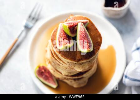 Pfannkuchen mit Ahornsirup und Feigen auf weiße Platte, Ansicht von oben, Soft Focus Stockfoto