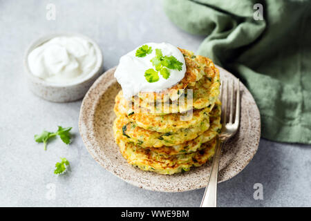 Vegetarisch zucchini Pfannkuchen oder Krapfen mit saurer Sahne auf dem Teller stapeln. Gesunde Vorspeise oder Snack Stockfoto