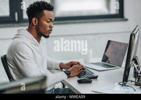 Selektiver Fokus der aufmerksamen afrikanische amerikanische Programmierer arbeiten am Computer im Büro Stockfoto