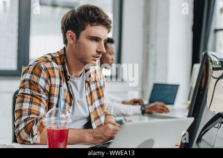 Selektiver Fokus der aufmerksamen Programmierer im Büro in der Nähe der afrikanischen amerikanischen Kollegen arbeiten Stockfoto