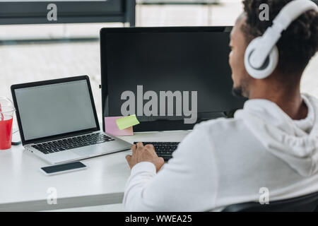 Rückansicht des afrikanischen amerikanischen Programmierer am Arbeitsplatz sitzen in Kopfhörer Stockfoto