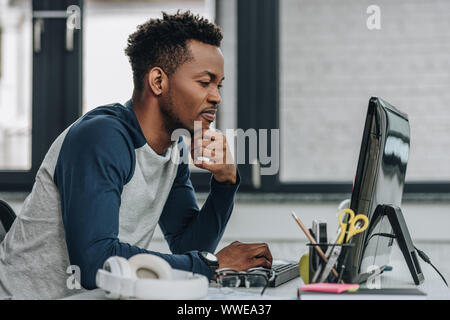 Aufmerksame afrikanische amerikanische Programmierer arbeiten am Computer im Büro Stockfoto