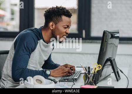 Aufmerksame afrikanische amerikanische Programmierer arbeiten am Computer im Büro Stockfoto