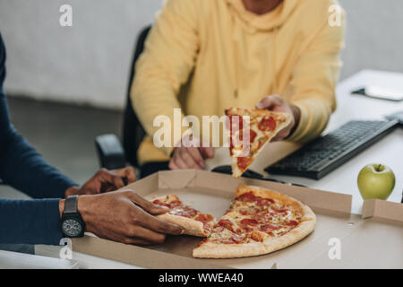 7/8-Ansicht von zwei multikulturelle Programmierer essen Pizza im Büro Stockfoto
