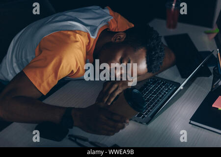 Müde afrikanische amerikanische Programmierer schlafen auf der Tastatur im Büro Stockfoto