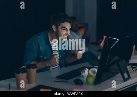 Wütend Programmierer gestikuliert während der Arbeit in der Nacht im Büro in der Nähe der afrikanischen amerikanischen Kollegen Stockfoto