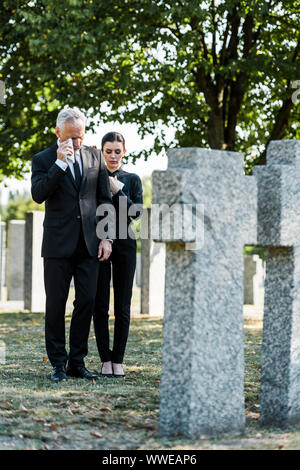 Verärgert Mann in der Nähe von Frau und Grabsteine in Friedhof schreien Stockfoto