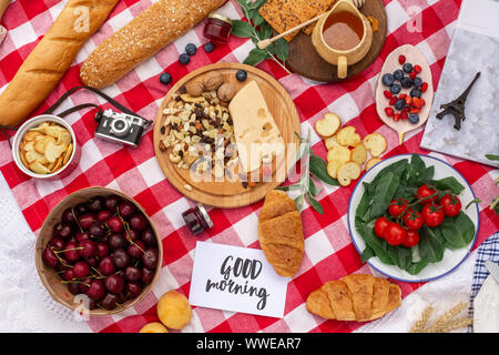 Stilvolles Picknick auf der grünen Wiese. Frische Croissants und eine Teekanne mit Tee auf eine Bettdecke in der Nähe eines Wicker weibliche Hut. Instagram Inhalt. Stockfoto