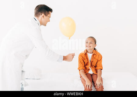 Kinderarzt in weißen Mantel, gelber Ballon zu Kind in der Klinik Stockfoto