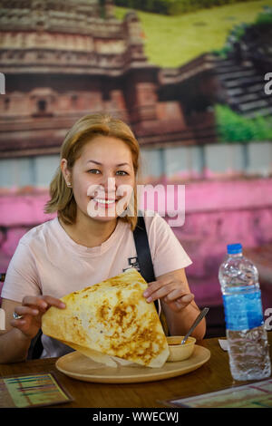 Mädchen isst Dosa. Traditionelle indische Gericht. Populäre Südindische Speisen Stockfoto