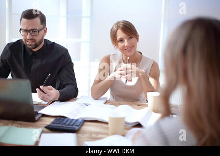 Bis zu schließen. Kollegen am Schreibtisch sitzen. Stockfoto