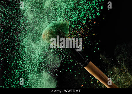Kosmetik Pinsel mit grünem Pulver Explosion auf schwarzem Hintergrund Stockfoto