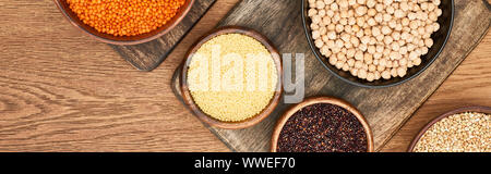 Panorama-aufnahme der Schüsseln mit Couscous, rote Linsen, Kichererbsen und schwarz Quinoa auf hölzerne Schneidbretter Stockfoto