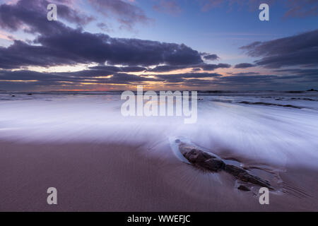 Wellen waschen über den Sand bei welcombe Mund Beach, North Devon Stockfoto