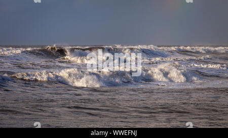 Stürmische Meere bei Westward Ho in North Devon, England mit Regenbogen am Horizont. Stockfoto