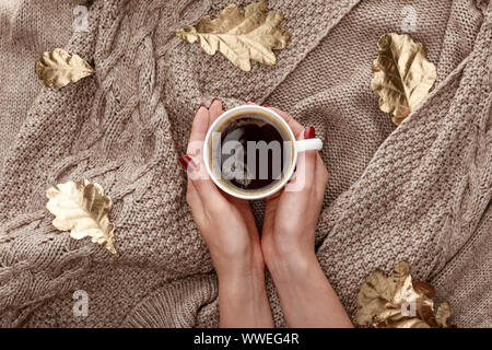 Teilweise mit Blick auf die Frau mit Becher mit Kaffee auf gestrickte Pullover braun mit goldenen Blätter Stockfoto