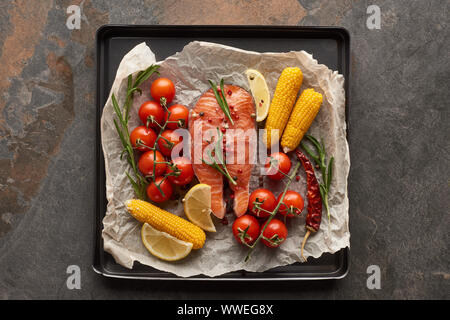 Blick von oben auf die rohen Lachs mit Gemüse, Zitrone und Rosmarin in Backblech Stockfoto